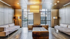 A modern lobby with a central seating area, large windows, and a wooden floor.
