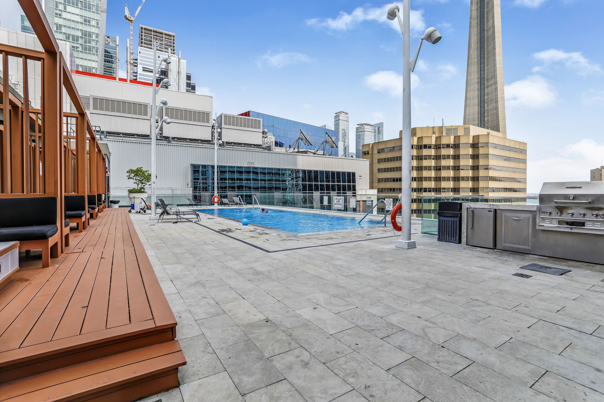 Zona de piscina en la azotea con vistas a edificios modernos, incluyendo una torre alta.