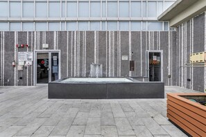 Un espace extérieur doté d’un mur recouvert de carreaux, d’un élément décoratif aquatique et d’un comptoir d’accueil.