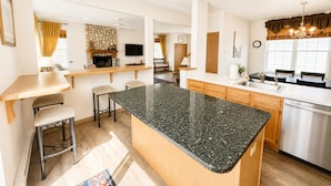 Een moderne keuken met een granieten eiland, houten kasten en een inbouwvaatwasser.