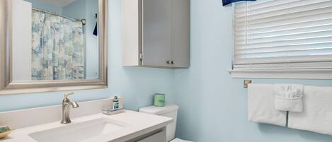 A bathroom with a sink, toilet, and mirror.