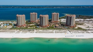 A high-rise hotel complex with multiple buildings, a beach, and a body of water. - Portofino Island Resort 1- 809 (Pensacola Beach)