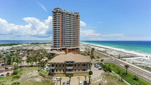A high-rise hotel with a beach view, featuring a prominent building with balconies and a smaller structure in front. - Portofino Island Resort 1- 809 (Pensacola Beach)