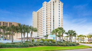A multi-story hotel with a flat roof, surrounded by palm trees and a well-maintained lawn. - Belle Mer 1102 (Navarre)