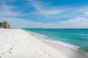 A beach with white sand, a pier, and buildings in the background. - Belle Mer 1102 (Navarre)