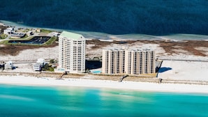 An aerial view of a coastal hotel with multiple high-rise buildings, a beach, and a marina. - Belle Mer 1102 (Navarre)