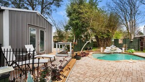 A backyard with a pool, a wooden deck, and a metal building. - Village Oasis (Gulf Breeze)