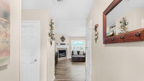 A hallway with a fireplace, a couch, and a mirror. - Village Oasis (Gulf Breeze)