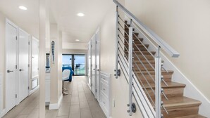 Ein moderner Flur mit einer Holztreppe, weißen Türen und Blick auf einen Balkon.
