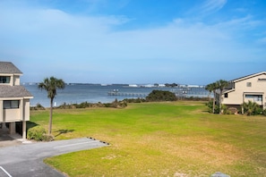 A residential area with a grassy lawn, a paved driveway, and a view of the ocean and a pier in the distance. - Santa Rosa Dunes 425 (Pensacola Beach)