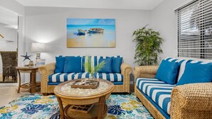 Quarto com móveis de vime, pintura de barcos, decoração de estrela-do-mar e uma planta.
