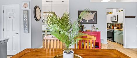 A dining area with a wooden table, a potted plant, and a map on the wall.