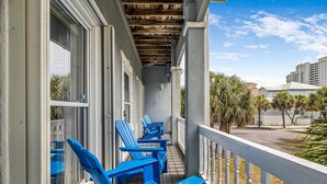 Ein Balkon mit blauen Adirondack-Stühlen und Blick auf Palmen und Gebäude.