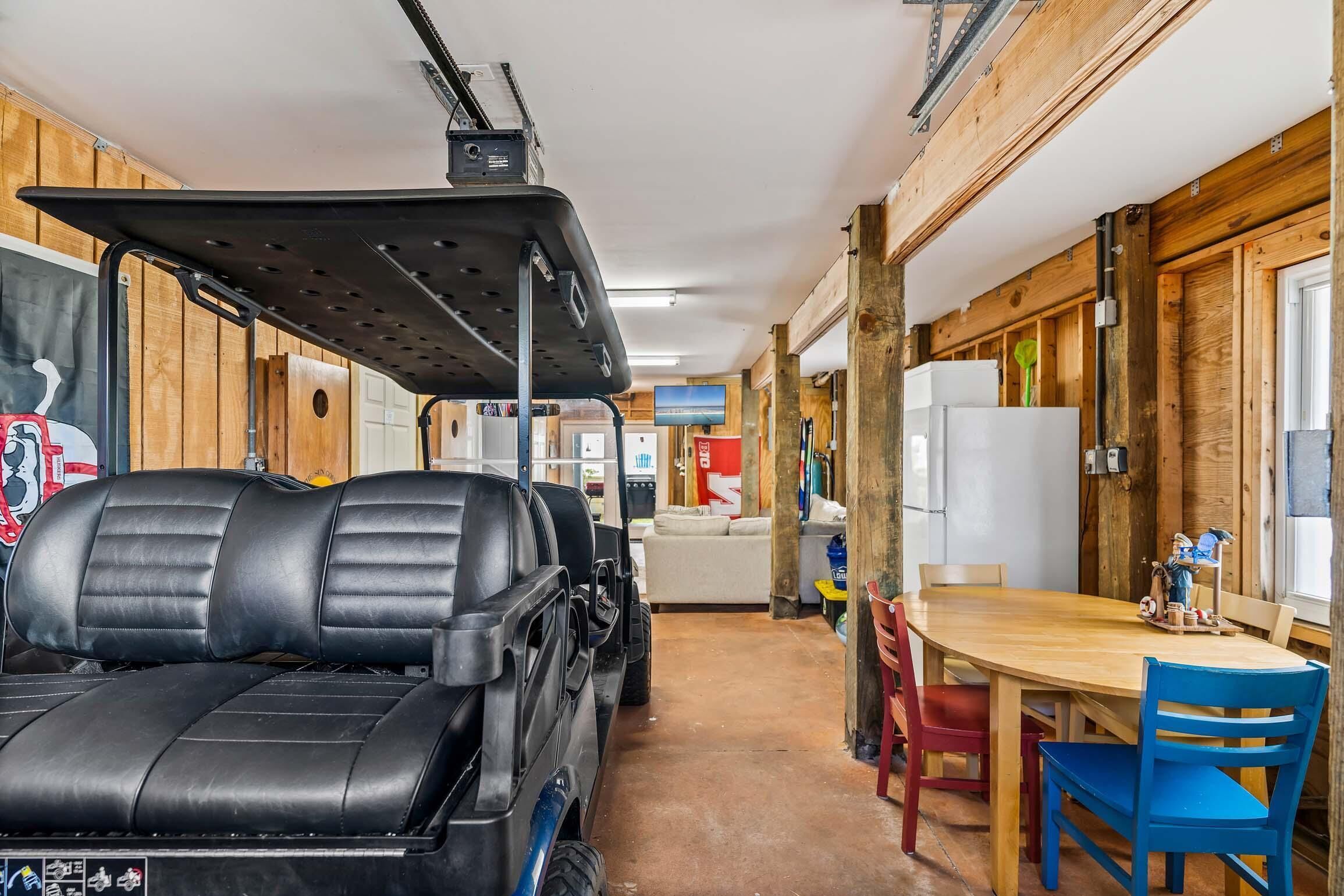 Quarto com decoração em madeira, uma mesa com cadeiras e um carrinho de golfe.