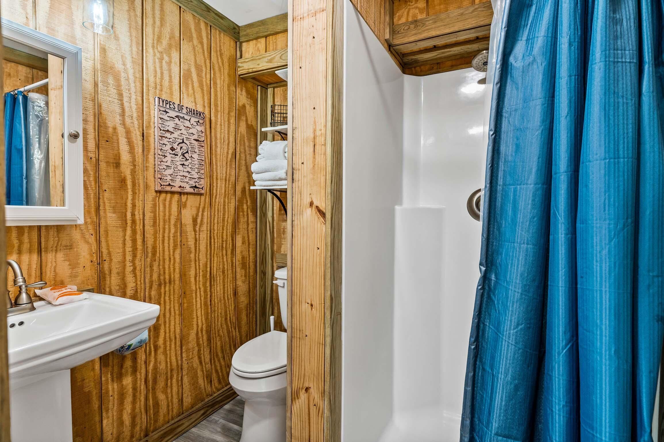 Un baño con paneles de madera, un lavamanos blanco, un inodoro y una cortina de ducha.
