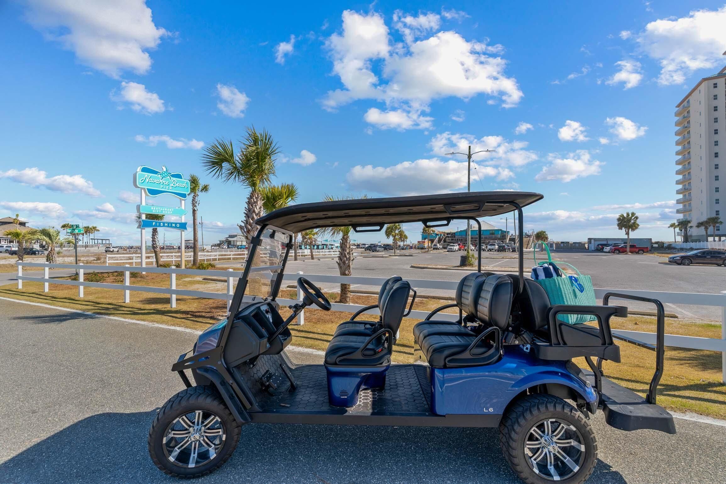 A golf cart parked on a road with a sign for 'Navvy Beach Fishing' in the background.