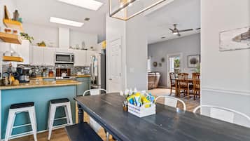 Een moderne keuken met witte kasten, een zwart aanrecht en een eethoek met een donker houten tafel en witte stoelen.