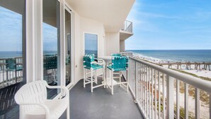 A balcony with a view of the beach, white chairs, and a table. - Summerwind Center 704 (Navarre)