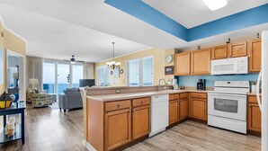 A modern kitchen with wooden cabinets, a dishwasher, a microwave, and an oven. - Summerwind Center 704 (Navarre)