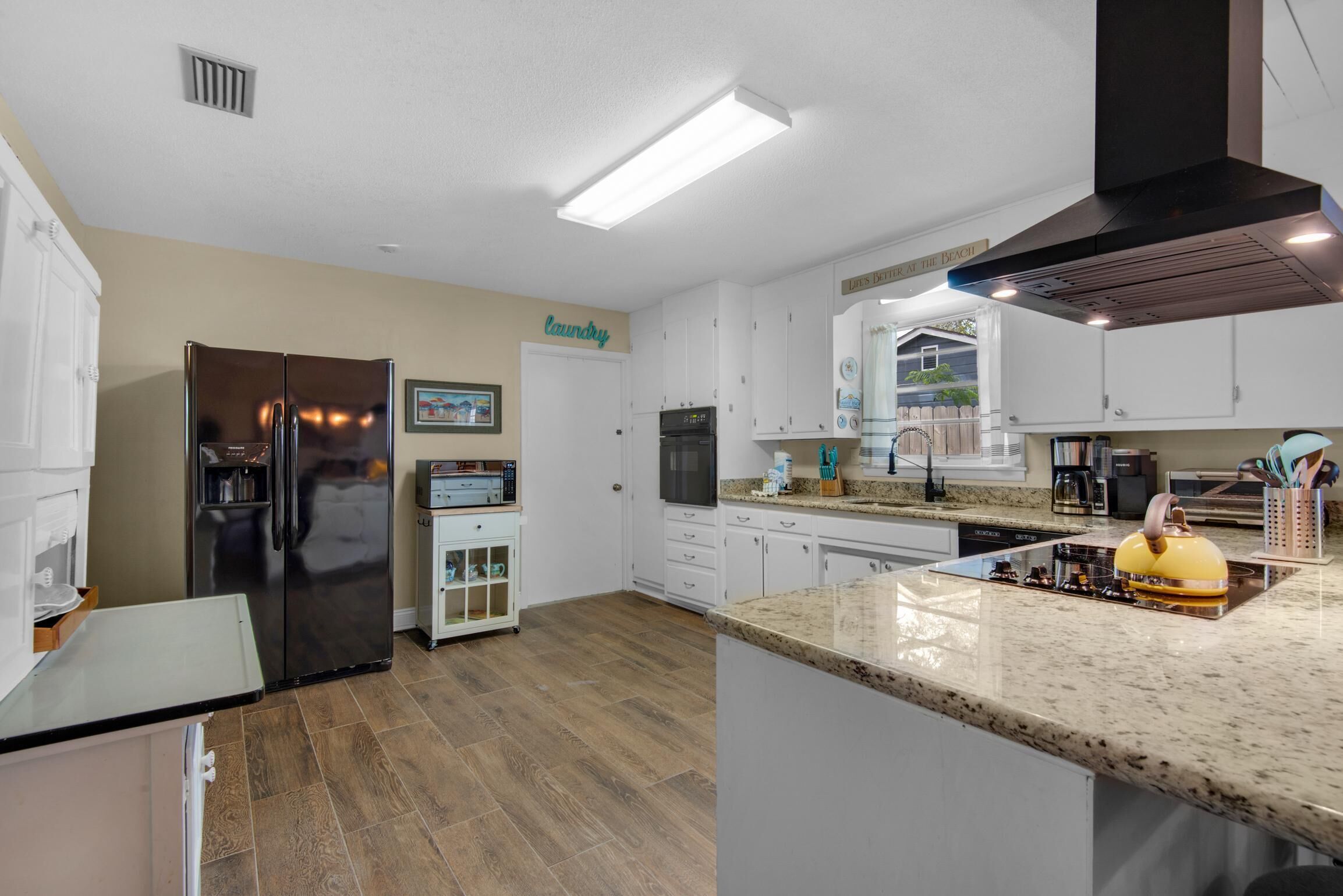 A modern kitchen with a stainless steel refrigerator, a built-in oven, and a granite countertop.