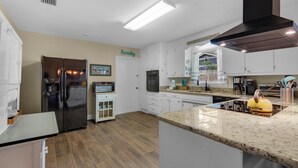 A modern kitchen with a stainless steel refrigerator, a built-in oven, and a granite countertop. - Bungalow By the Sea-starfish (Navarre)