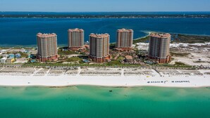 A high-rise hotel complex with multiple buildings, a beach, and a body of water. - Portofino Island Resort 5-1708 (Pensacola Beach)