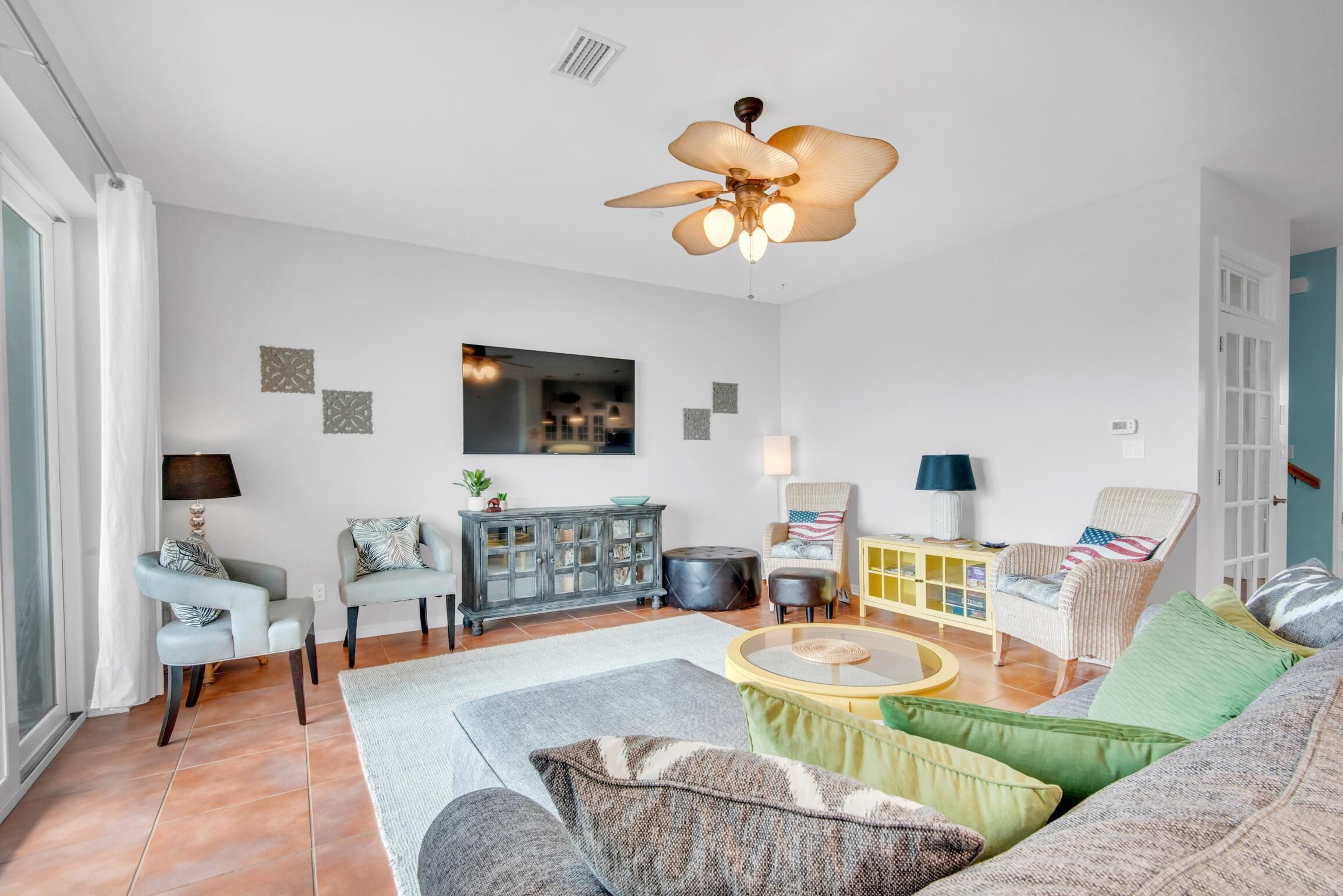 Un salon spacieux doté d’un ventilateur de plafond, d’un ensemble de canapés, d’une table basse et d’un meuble.