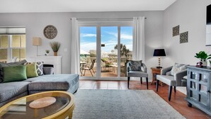 A living room with a sectional sofa, a coffee table, and a view of the outdoor patio. - Bonita Bay (Pensacola Beach)