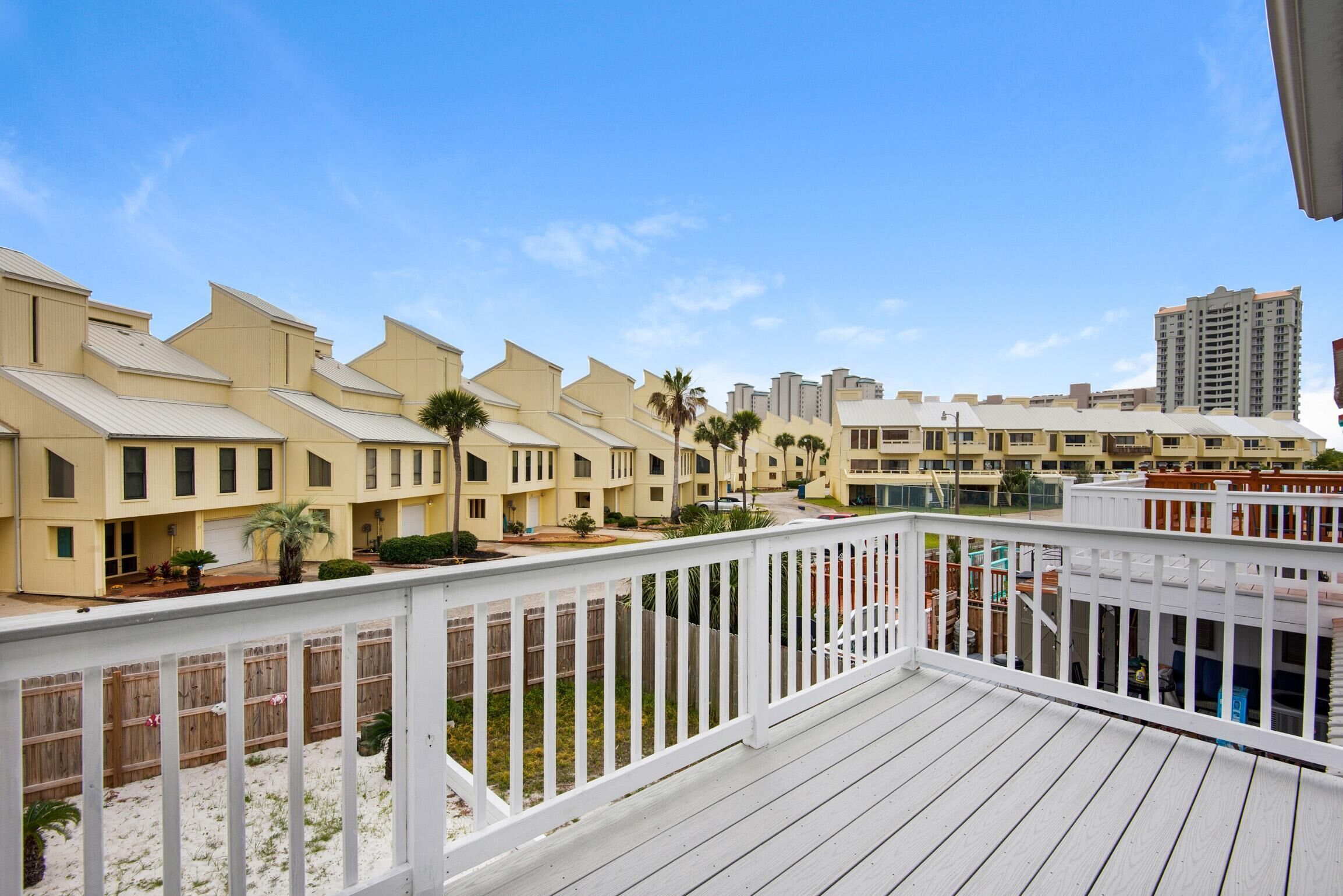 A hotel with a white balcony, beige buildings, and a clear blue sky.