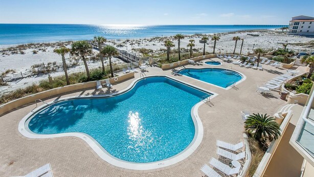 A resort with two swimming pools, beach views, and palm trees. - Emerald Isle Unit 206 (Pensacola Beach)