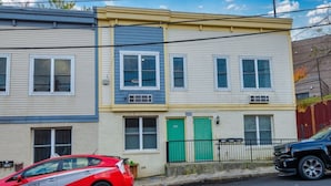 A row of townhouses with a green door, a black car parked in front, and a red car parked to the side. - Stylish DC Condo| Free Parking | Near Union Market (Washington)
