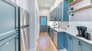 A kitchen with stainless steel appliances, blue cabinets, and a wooden floor. - Stylish DC Condo| Free Parking | Near Union Market (Washington)