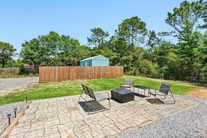 A backyard with a wooden fence, a shed, and outdoor seating with chairs and a table.