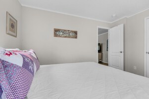 A bedroom with a large bed, a wooden wall decoration, and a door leading to a bathroom.