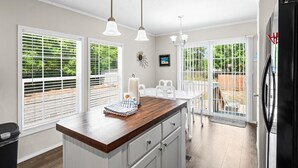 A kitchen with a wooden countertop, white cabinets, and pendant lights.