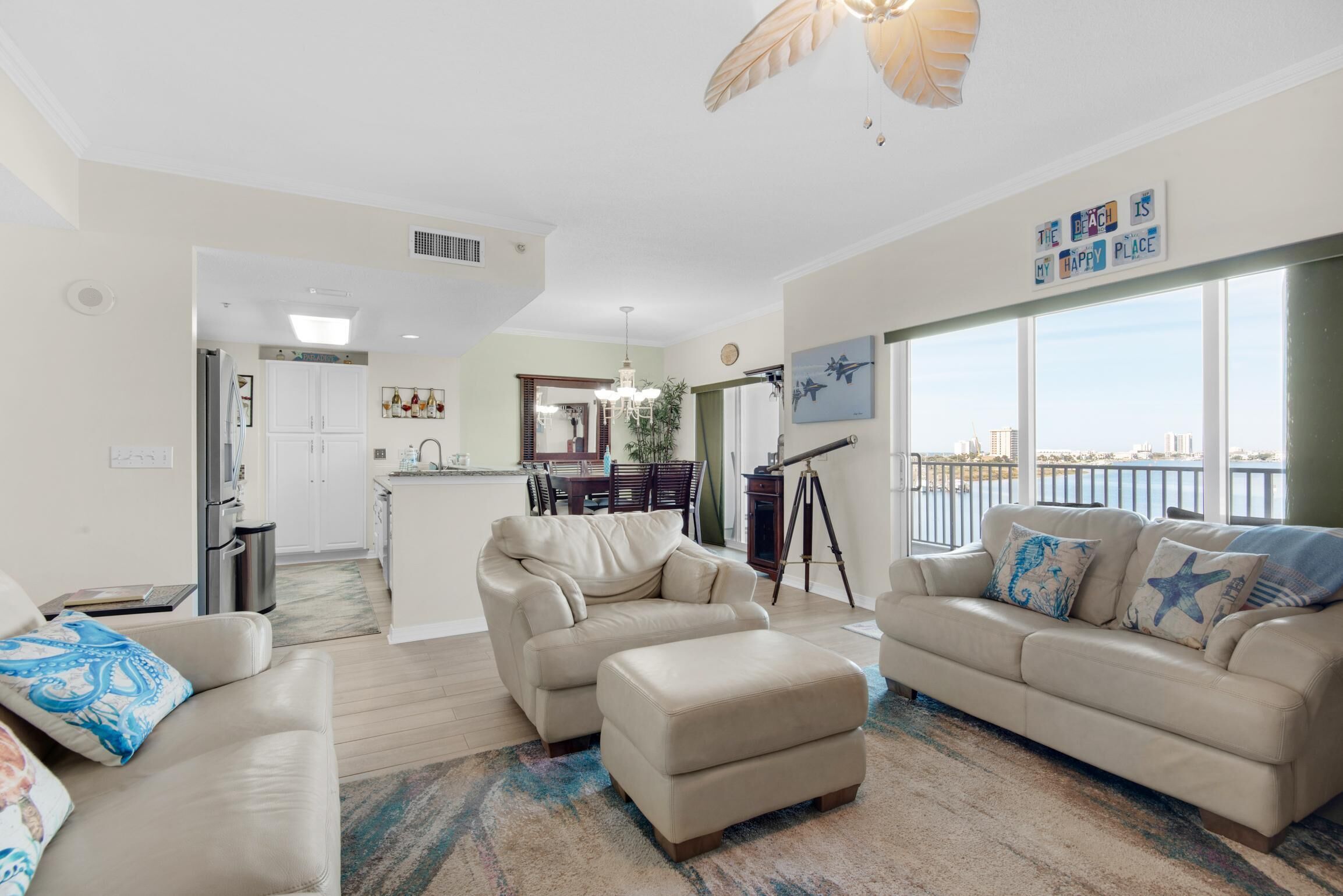 A spacious living room with two beige sofas, a coffee table, and a view of the city through large windows.