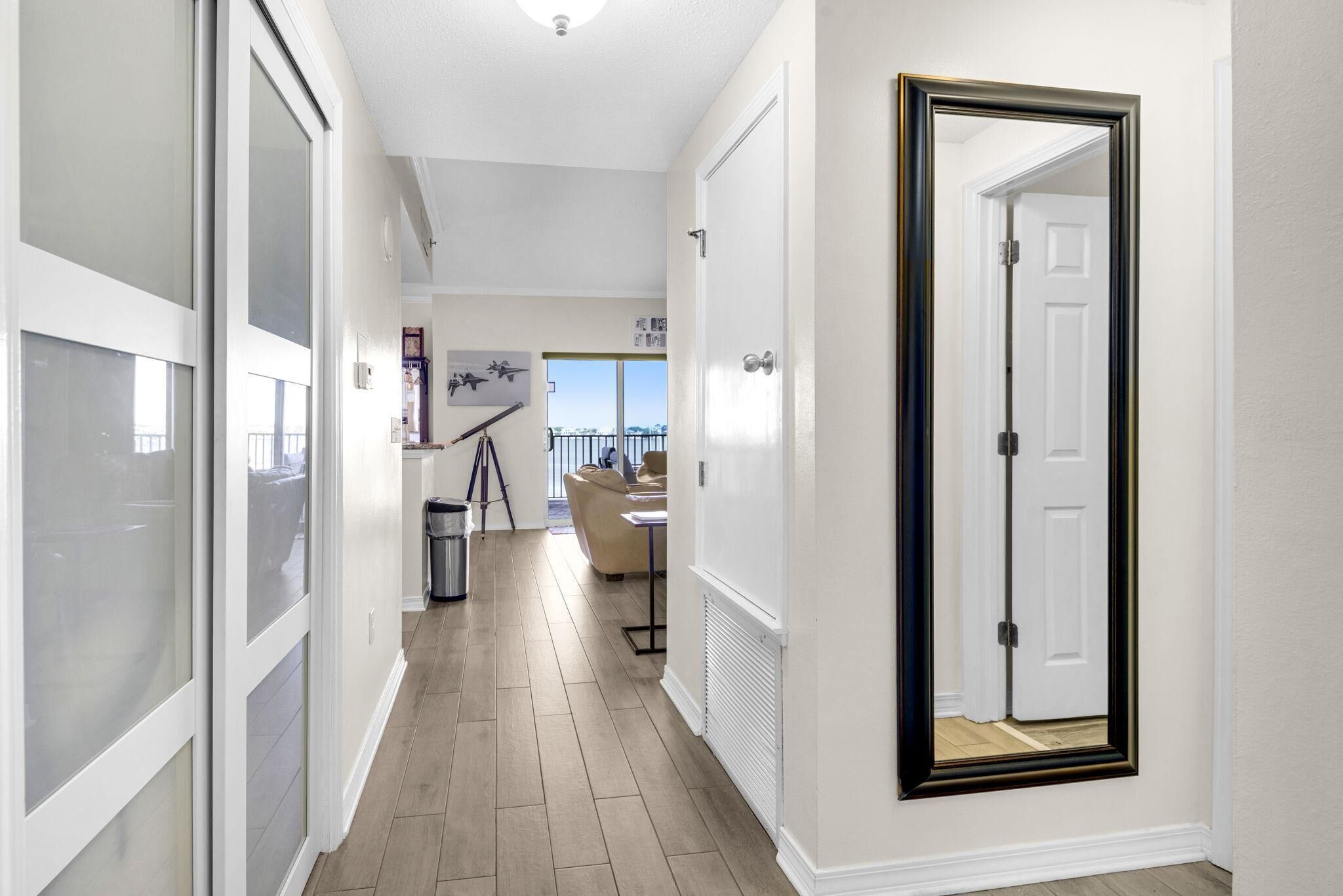 A hallway with a sliding door, a tripod, and a view of the balcony.