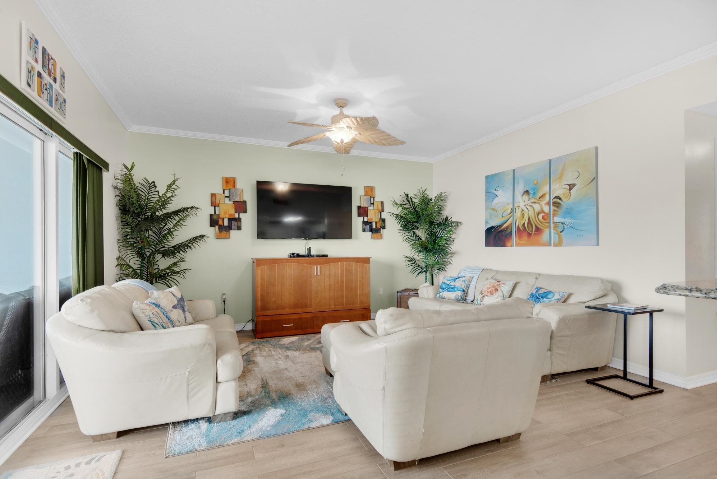 A living room with two sofas, a TV, a wooden cabinet, and a ceiling fan.