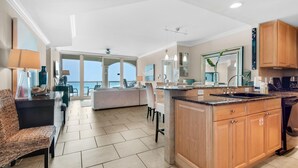 A spacious kitchen with a large island, wooden cabinets, and a view to the outside. - Portofino Island Resort 5-1002 (Pensacola Beach)