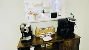 A kitchenette with a coffee maker, a basket of bread, and a microwave.