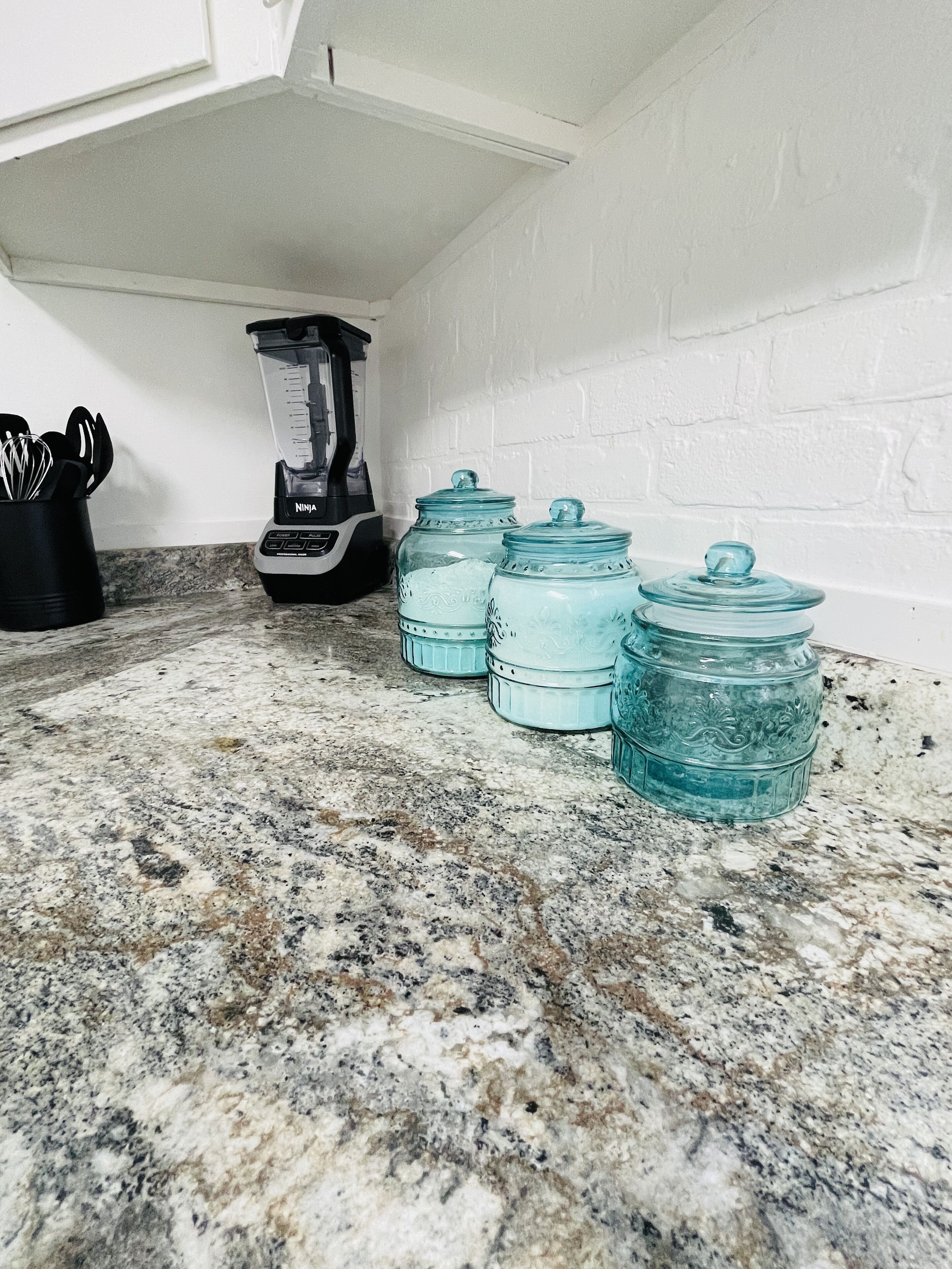 Eine Küche mit Granitarbeitsplatten, einem Mixer und blauen Glasbehältern.