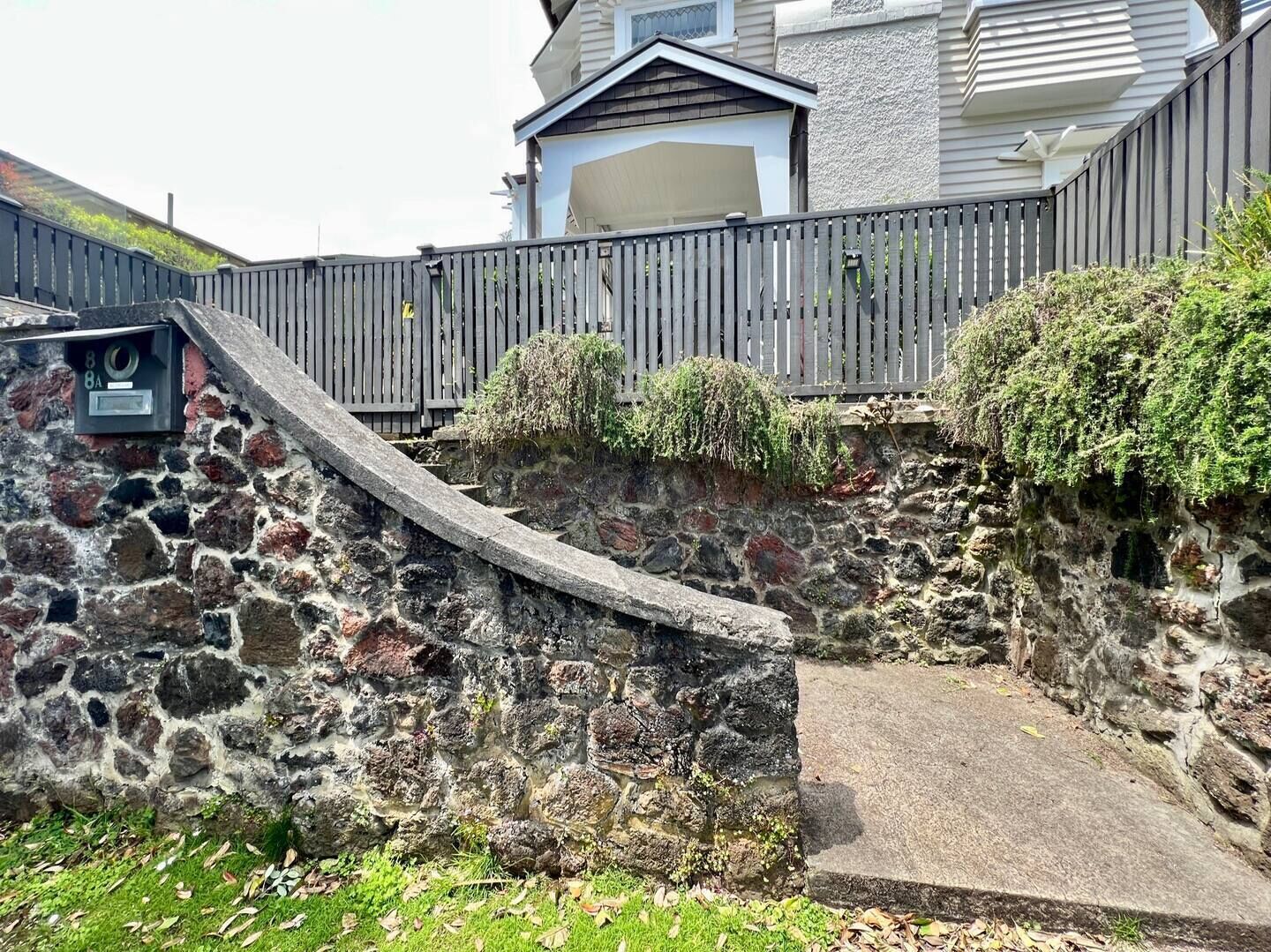 A stone retaining wall with a wooden fence and a mailbox.