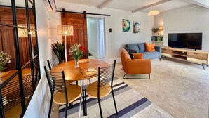 Uma sala moderna com área de jantar, sofá, televisão e escada.