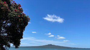 Uma praia com vista clara para o mar e uma ilha ao longe. Há um sinalizador com informações sobre a praia.