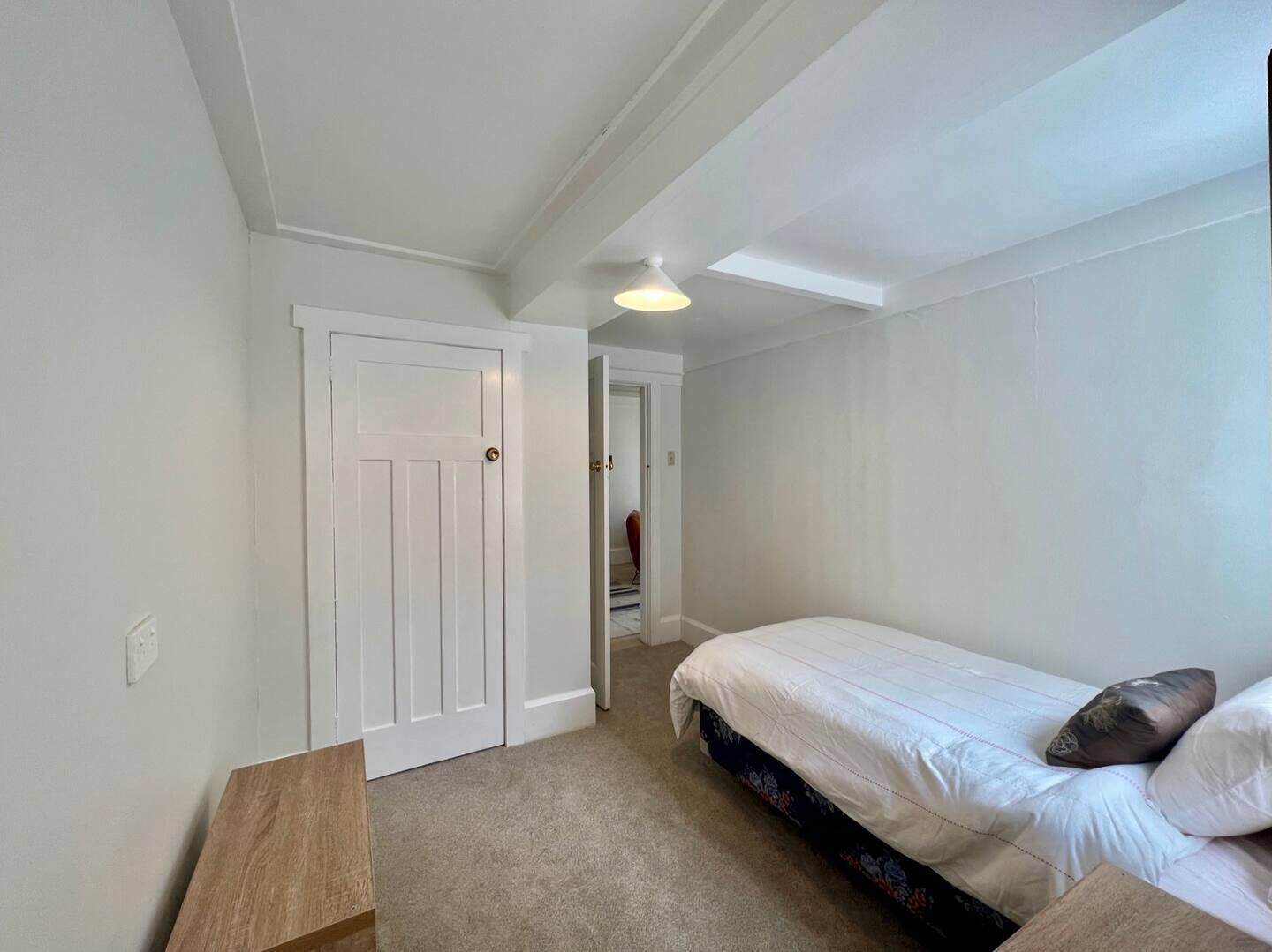 A bedroom with a bed, a wooden nightstand, and a closet.
