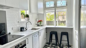 Cozinha moderna com armários brancos, bancada preta, lava-louças embutida e janela com vista para o exterior.