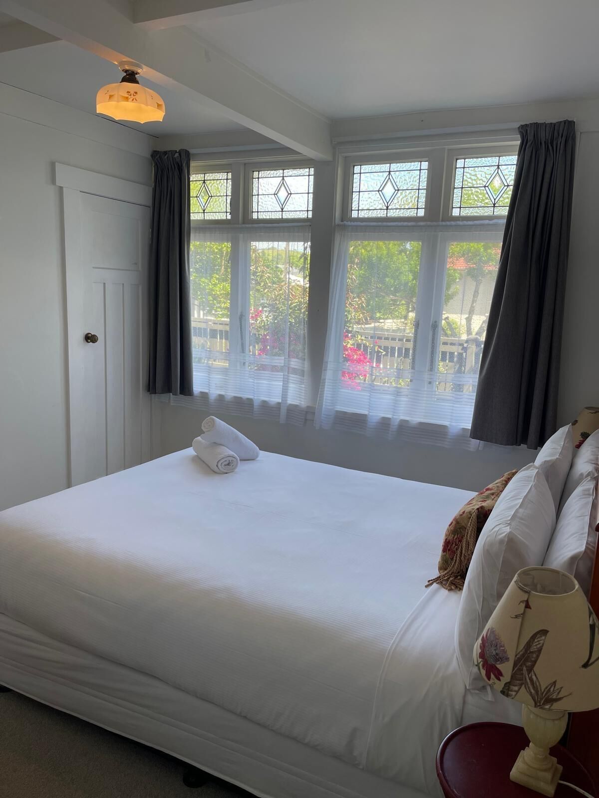 A bedroom with a bed, a nightstand, a lamp, and a window with curtains.