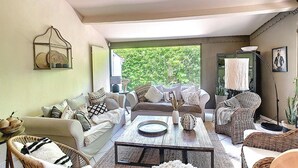 Ein geräumiges Wohnzimmer mit großem Fenster, Esstisch und bequemen Sitzgelegenheiten.