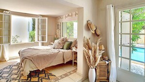 Ein Schlafzimmer mit Bett, Fenster, Spiegel und Blick auf einen Pool.