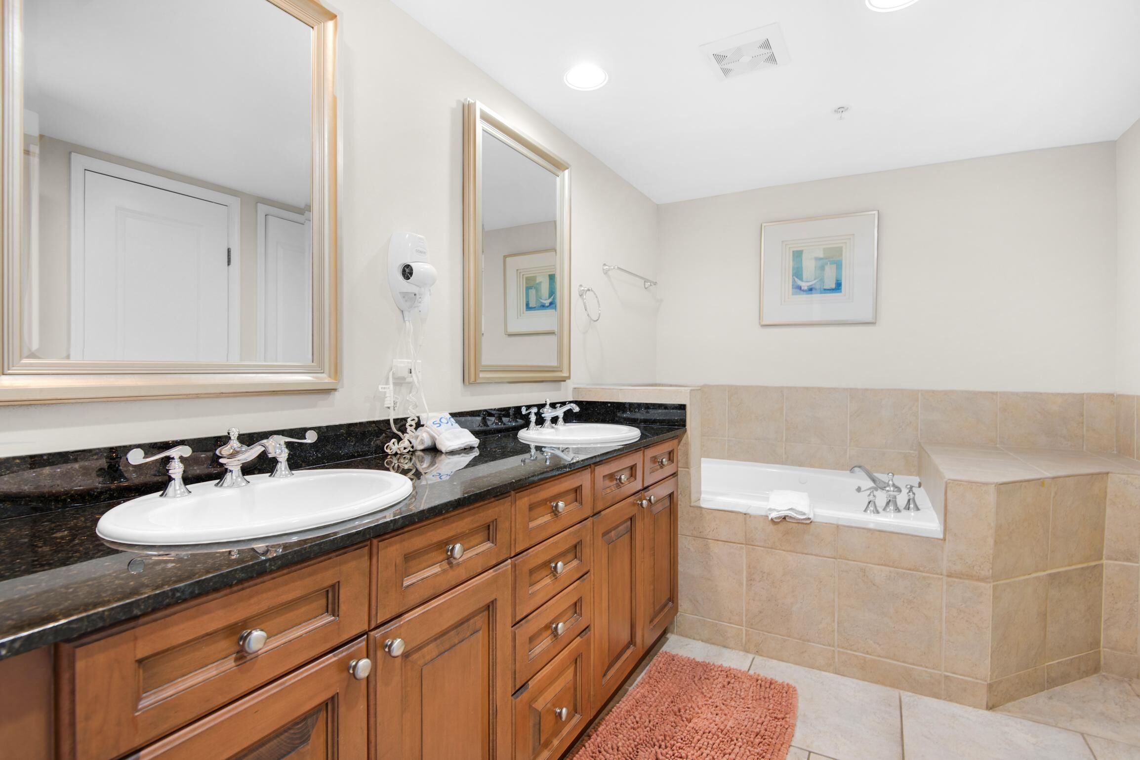 A modern bathroom with two sinks, a large mirror, a bathtub, and a shower.